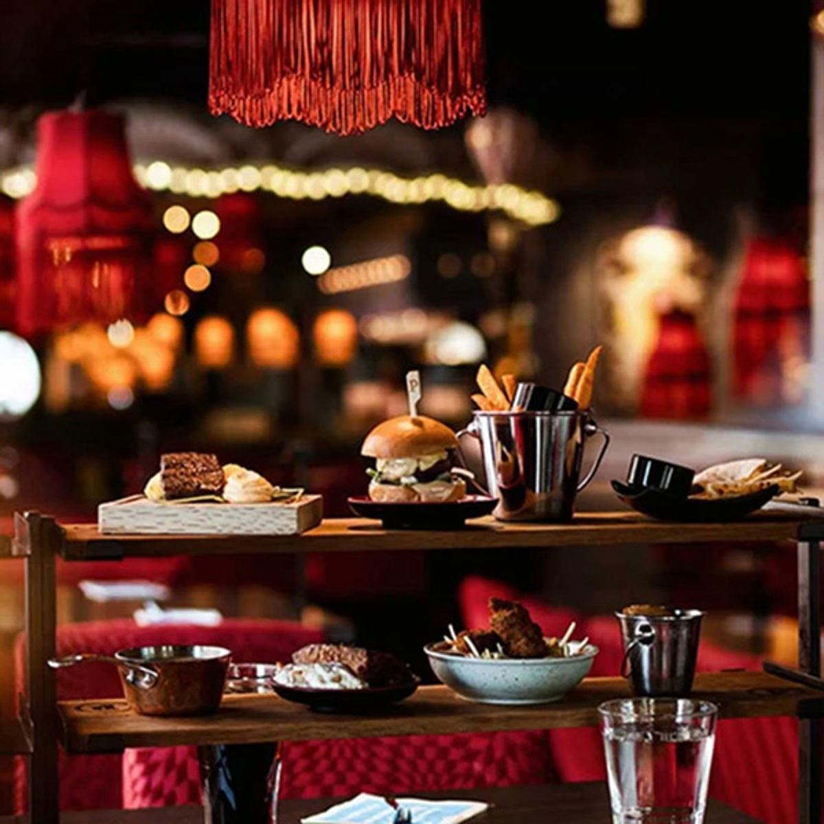 Gourmetburger og pommes frites serveret i en elegant restaurant med dæmpet belysning i baggrunden.