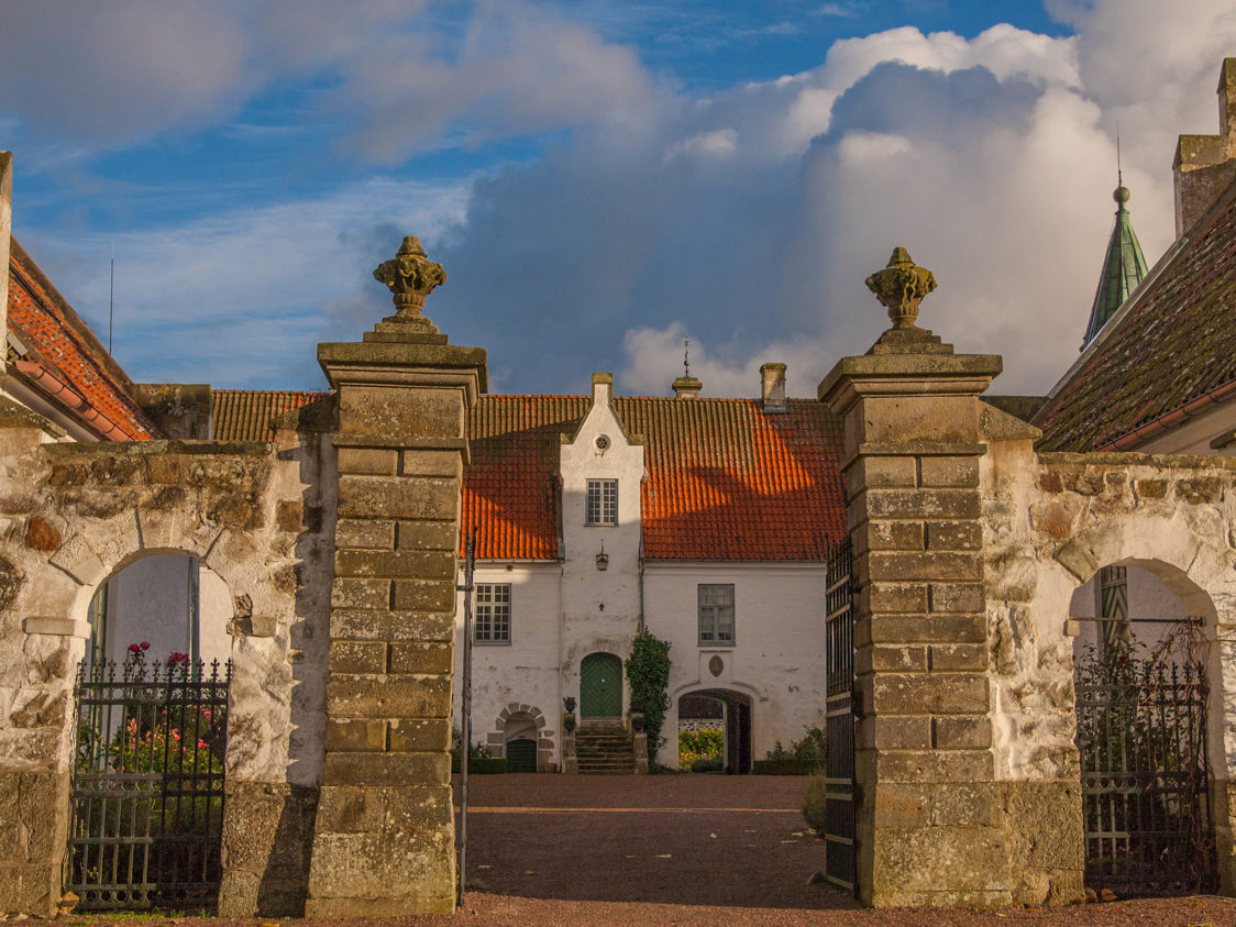 Riddersalen ved herregården Voergaard med historisk arkitektur og store stenkolonner i forgrunden.