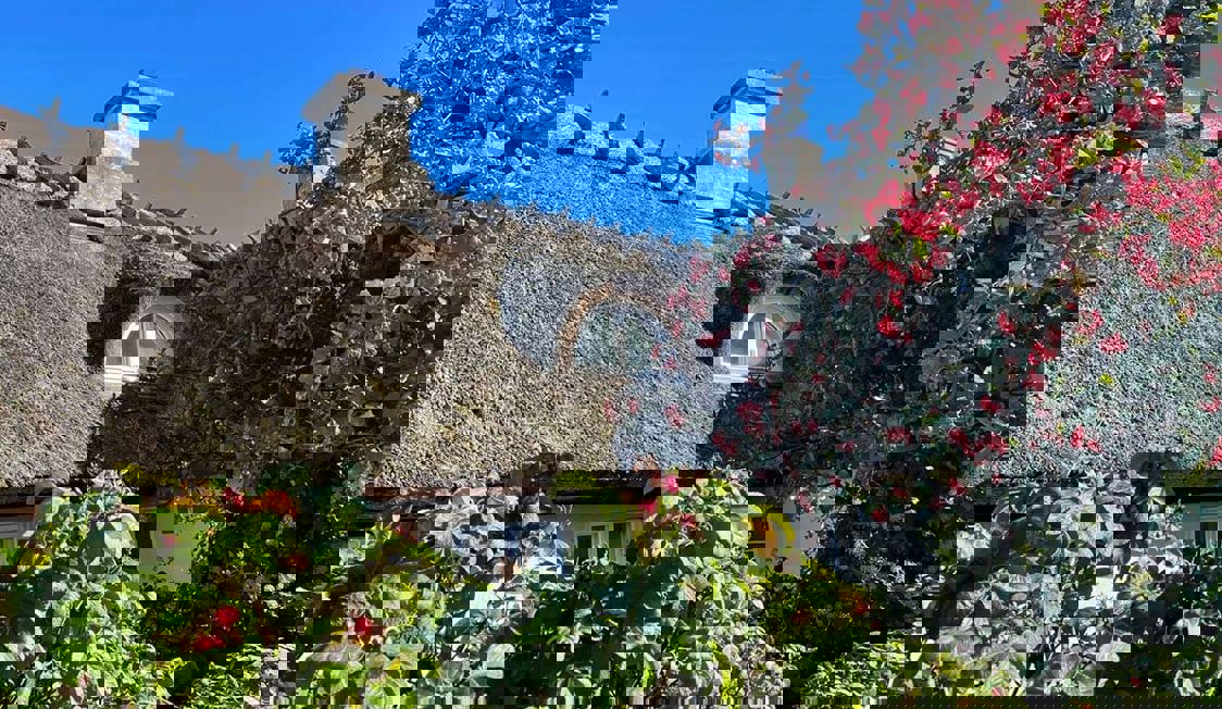 Taket på Monkerup Hus ses i solsken med blå himmel.