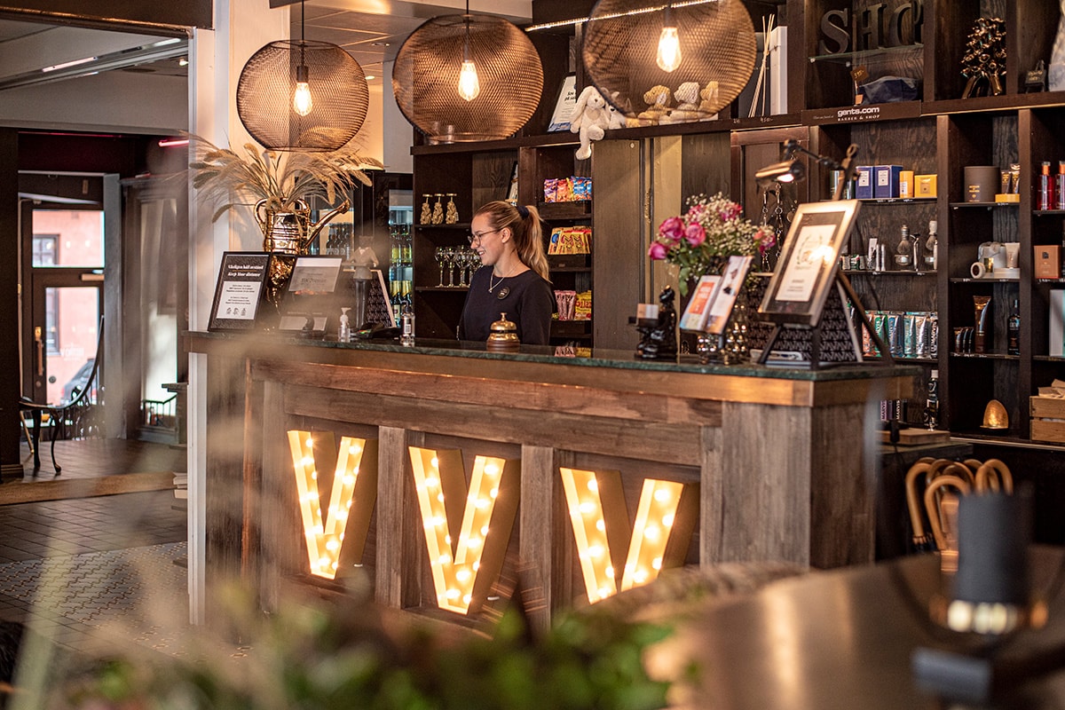 V Hotel reception ses med en kvindelig receptionist.