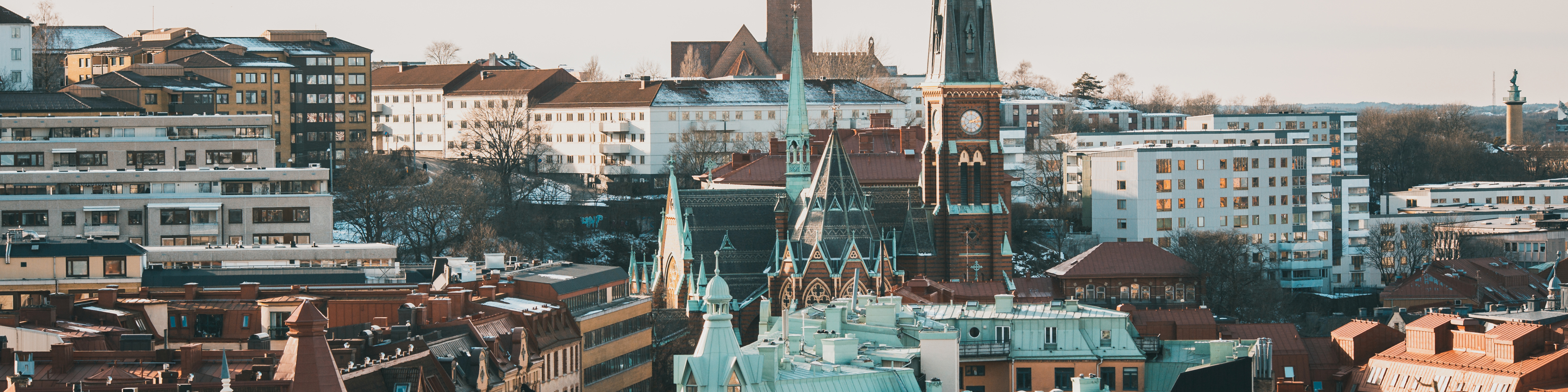 Göteborgs skyline set fra et fugleperspektiv, hvor kirketårnet skiller sig ud blandt de omgivende bygninger.