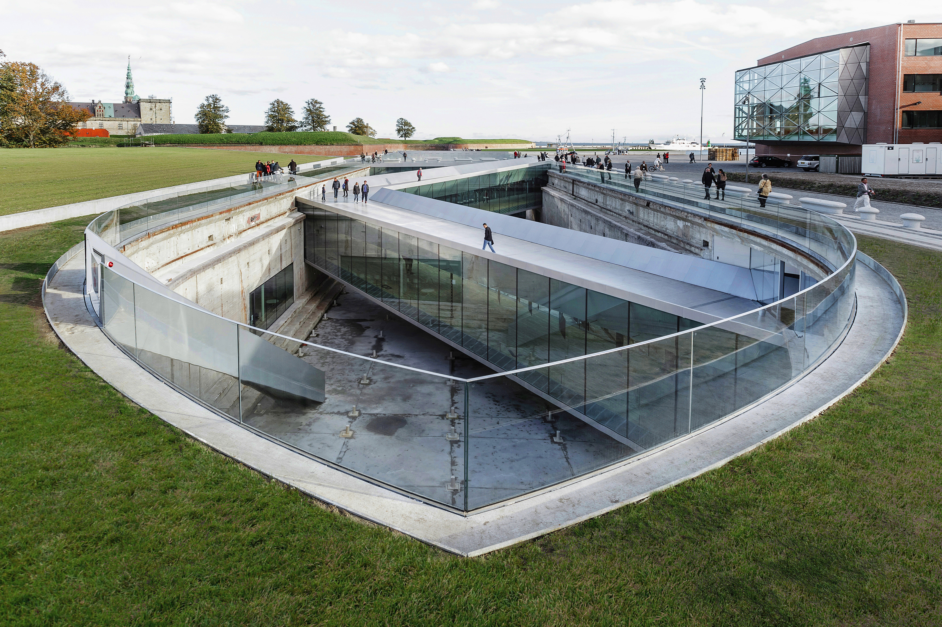 Museet för Sjöfart med modern glasdesign och folk som promenerar på gångvägen i soligt väder.