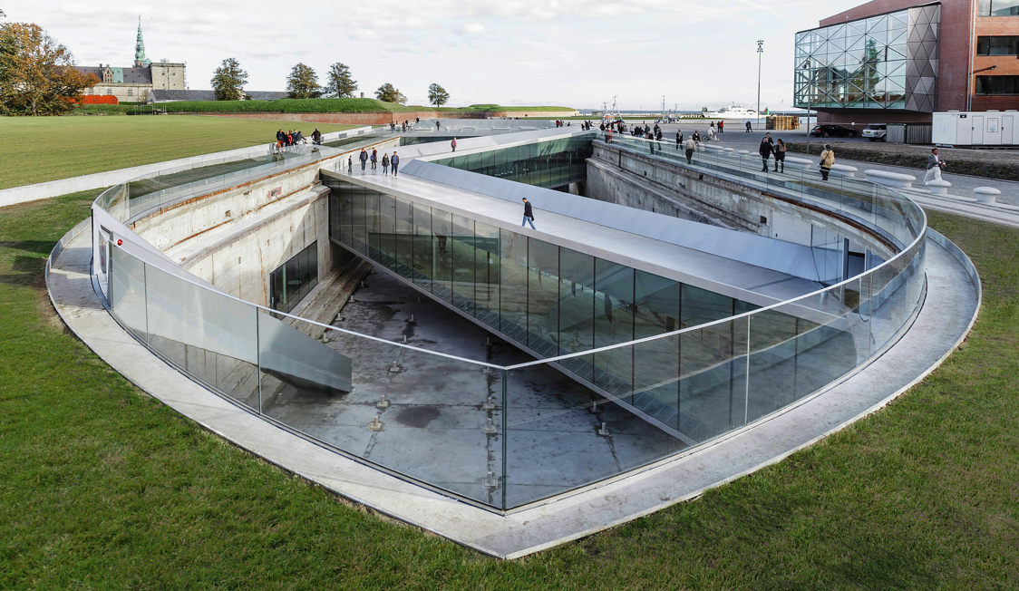 Museet för Sjöfart med modern glasdesign och folk som promenerar på gångvägen i soligt väder.