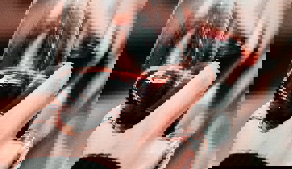 Två personer skålar med rött vin.