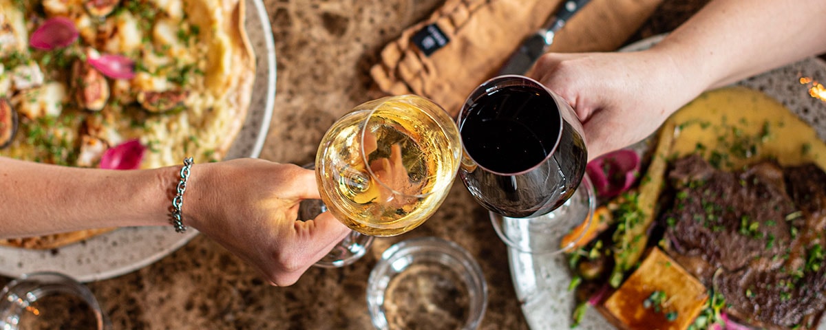 Blå glasvase med snoet design fyldt med frisk blomsterbuket, står på et rustikt træbord i naturligt lys.