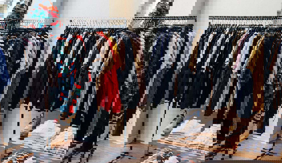 Kläder hänger på ställningar i en butik.
