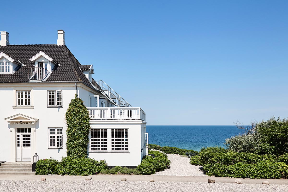 Sommar Riviera hus med trädetaljer och slingrande gångvägar omgivna av grönska och buskar i trädgården.