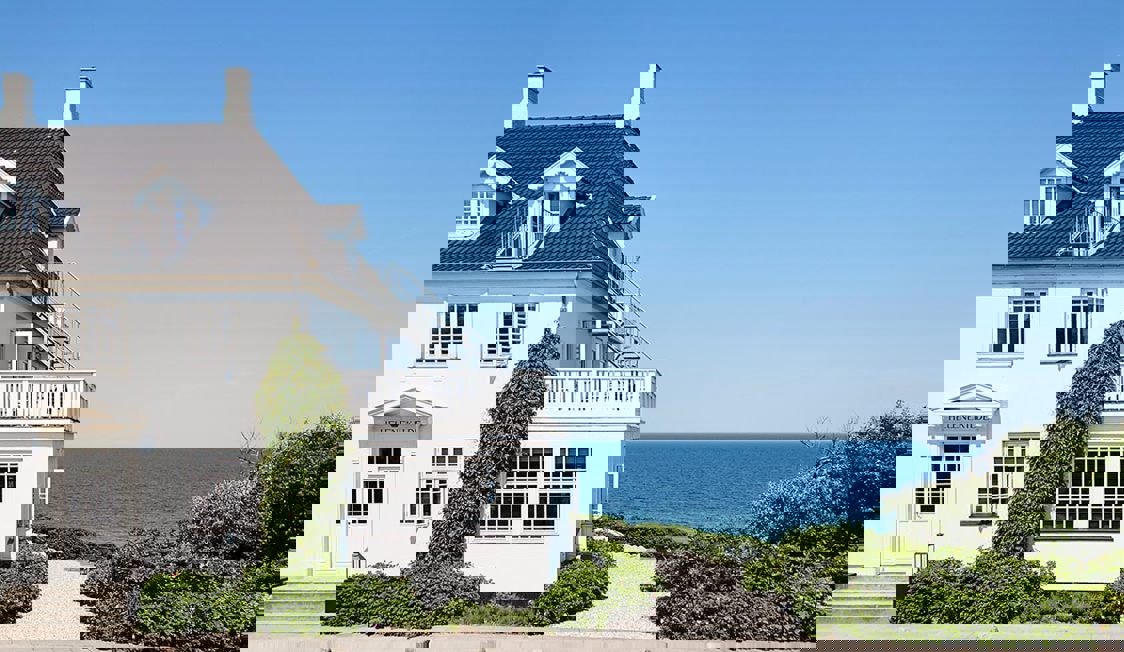 Sommar Riviera hus med trädetaljer och slingrande gångvägar omgivna av grönska och buskar i trädgården.