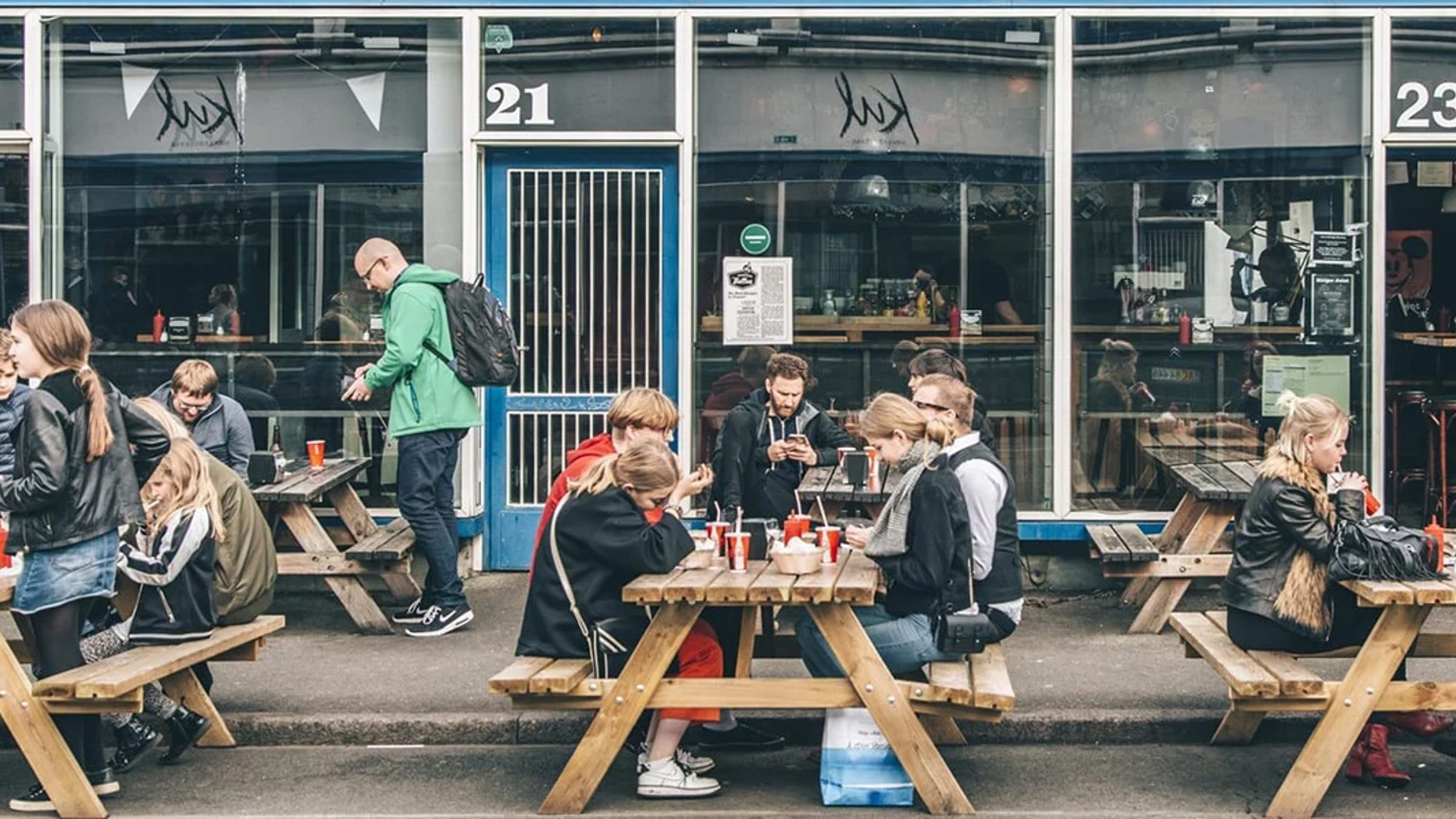 Utomhusbord med gäster som njuter av måltider utanför Kodbyen Tommis Burgerjoint.