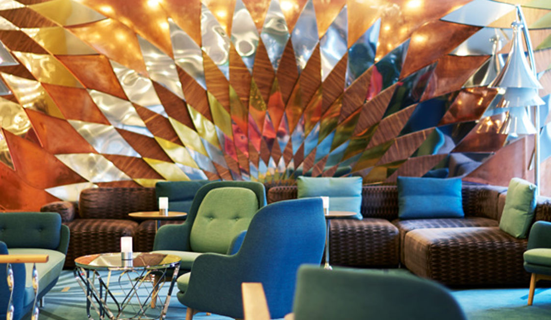 Komfortabel loungedel med färgglada geometriska väggdekorationer på Molslinjen Express 3.