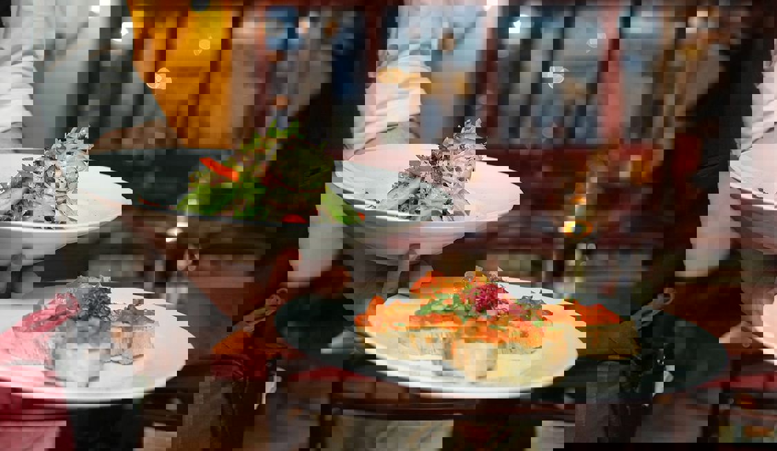 En servitör står med två tallrikar på en restaurang.