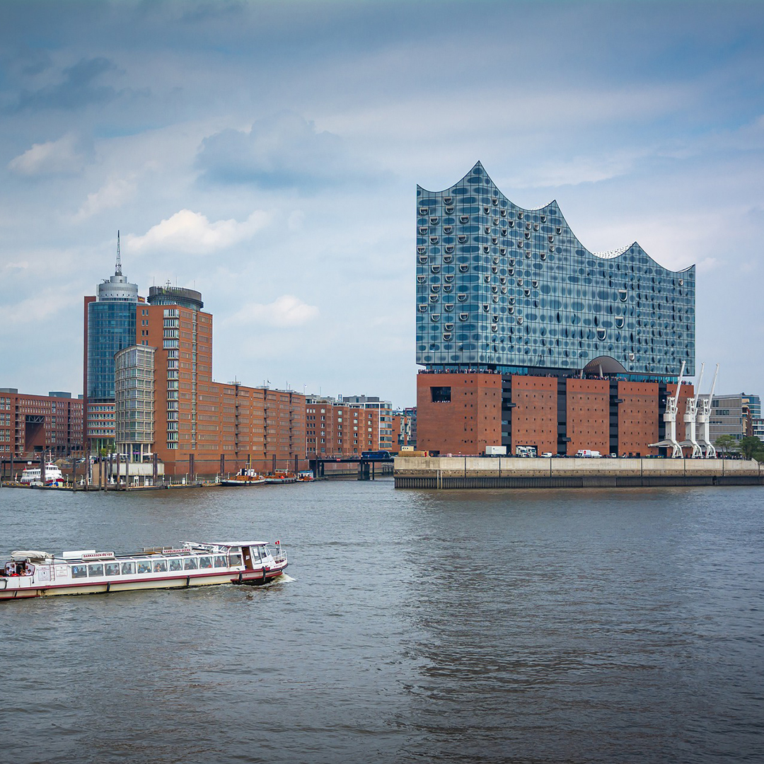 Elbphilharmonien i Hamburg med ett kryssningsfartyg seglande på floden i förgrunden.