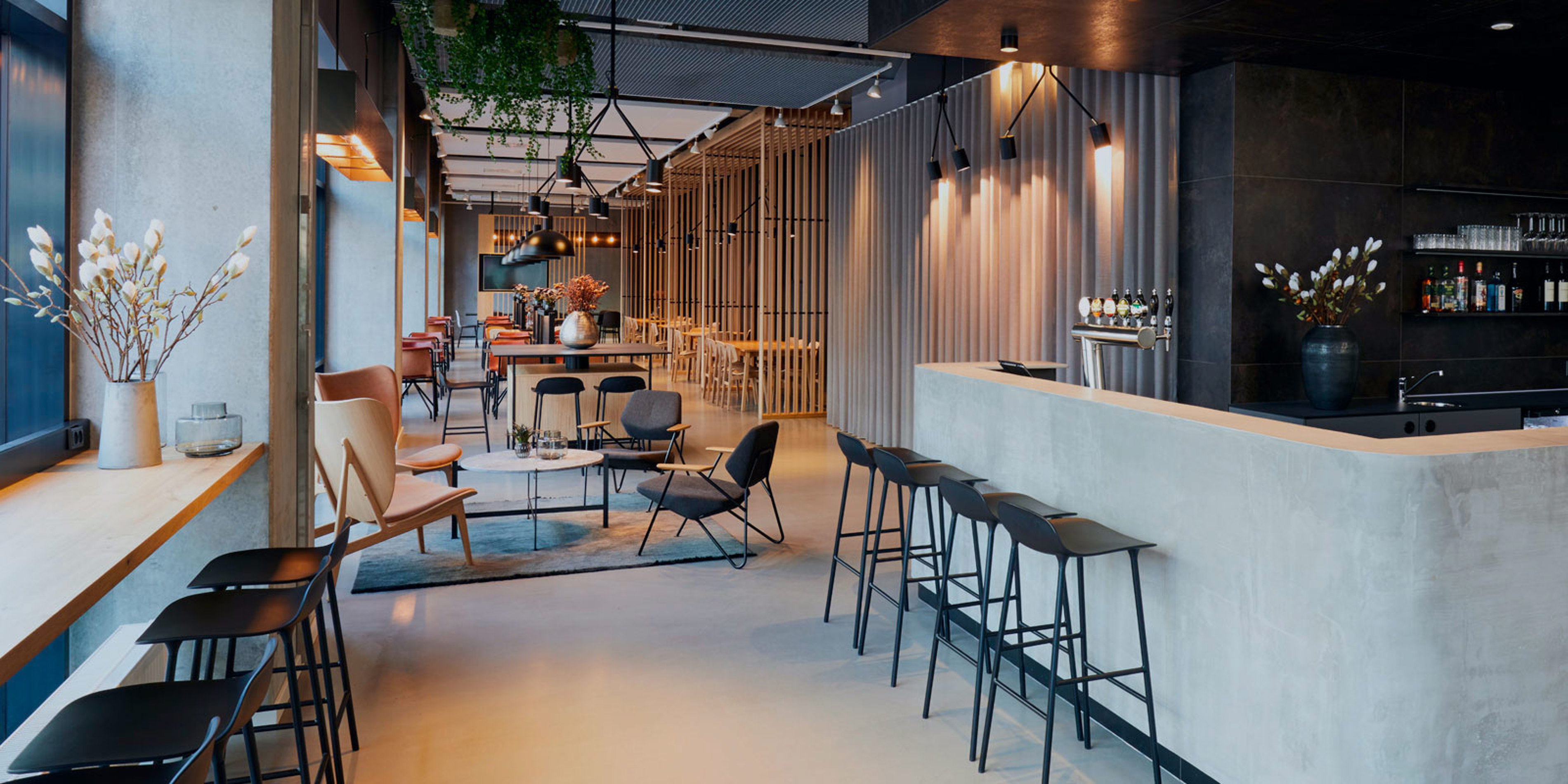 Moderne caféindretning med sort bar og stilfulde stole i et lyst og indbydende lokale.