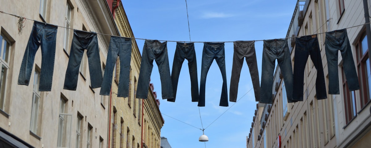 Jeans hænger til tørre på line mellem bygninger i frøperspektiv.