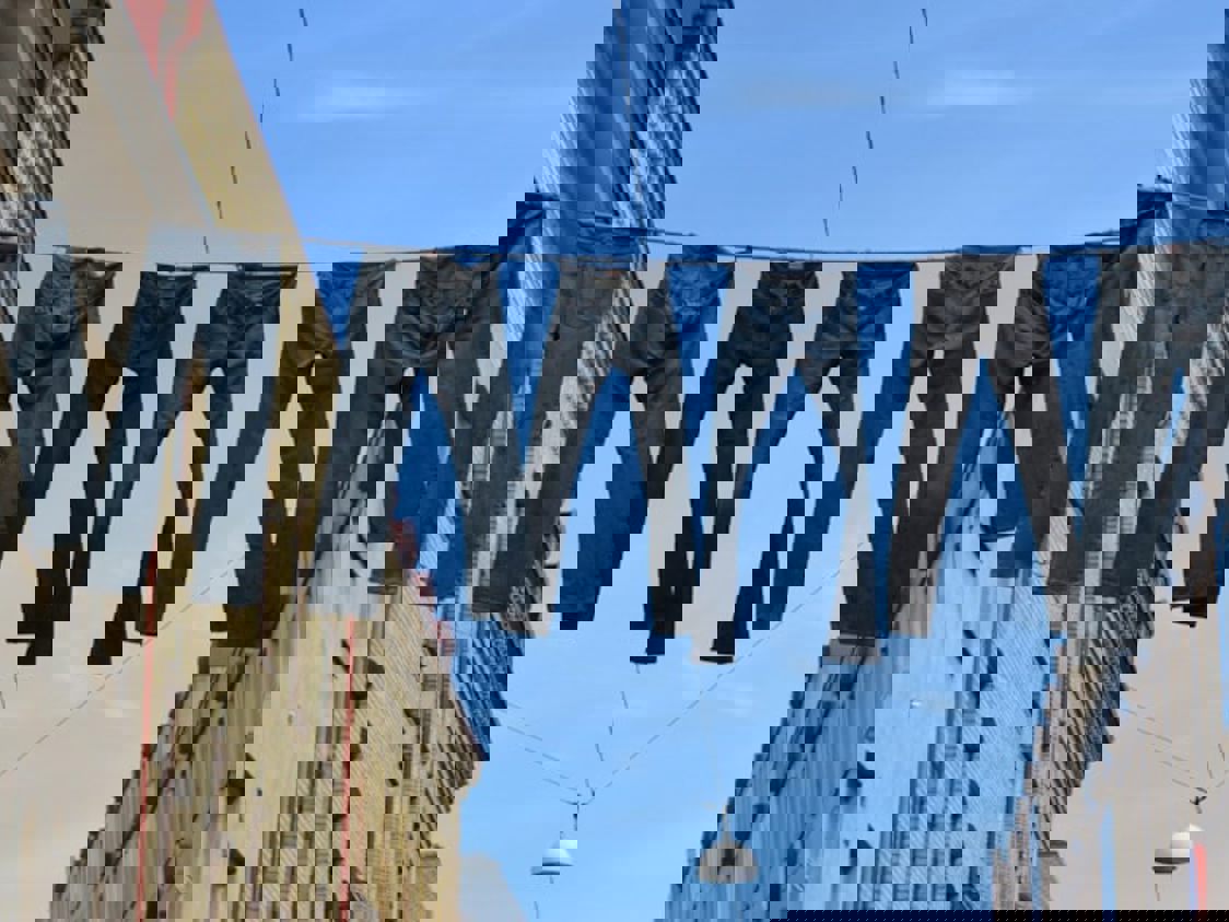 Jeans hænger til tørre på line mellem bygninger i frøperspektiv.