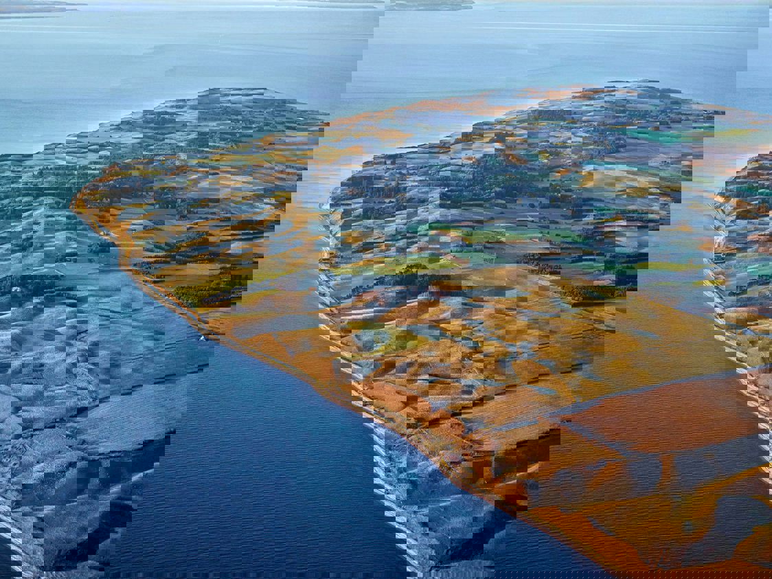 Luftfoto af Samsø med fokus på grønt landskab og lyseblå himmel.