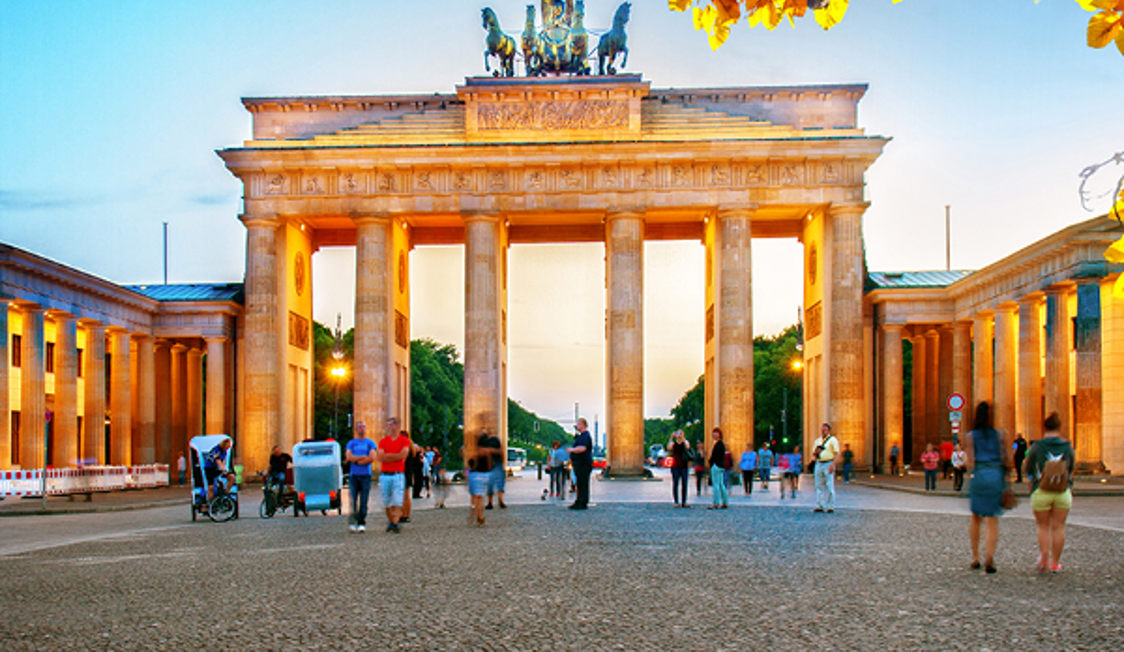 Brandenburger Tor i Berlin vid skymningen med människor promenerande på torget.