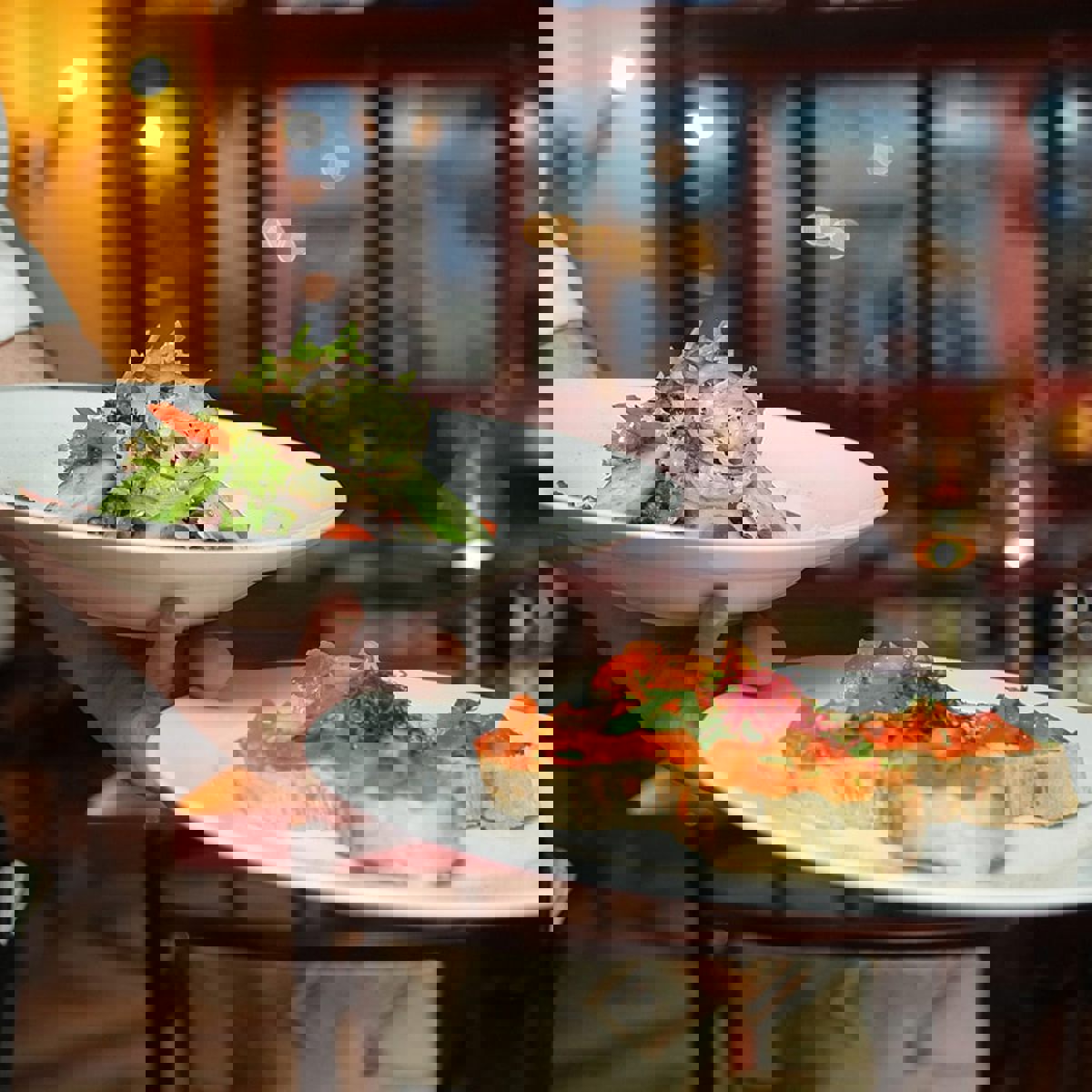 En servitör står med två tallrikar på en restaurang.