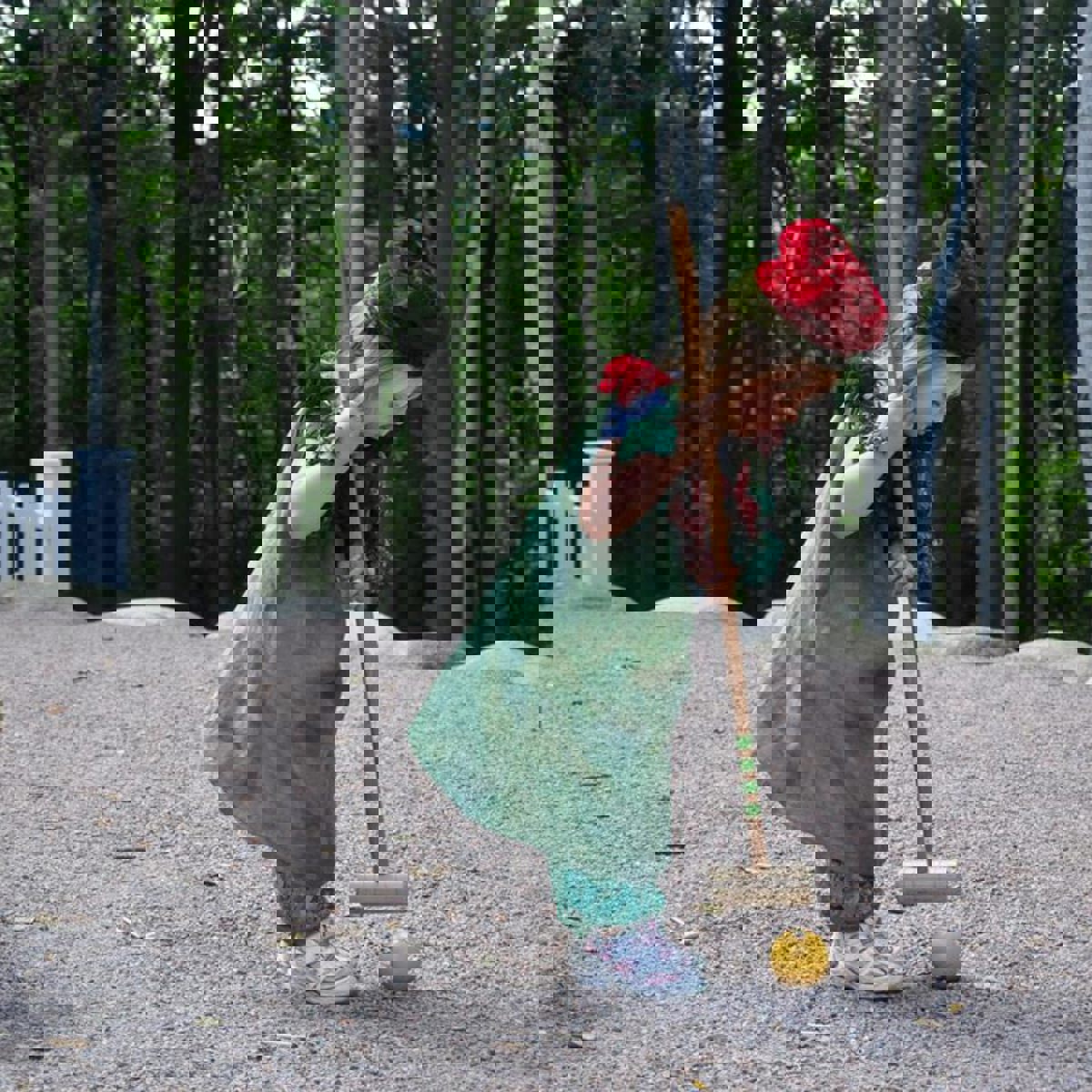 Et barn spillet cricket med træer og skov i baggrunden.