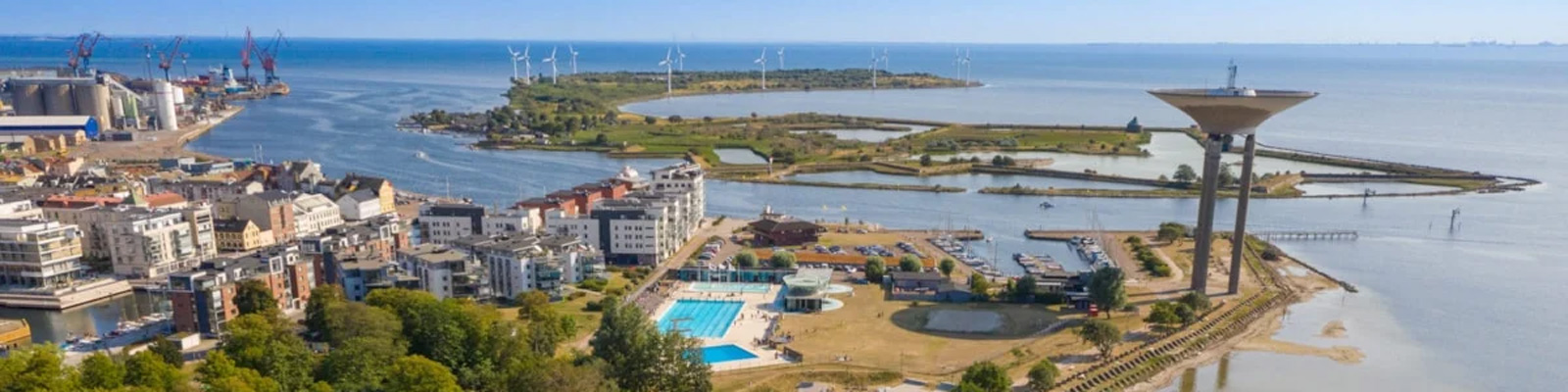 Panoramaudsigt over Kalundborgs kystlinje med ikonisk vandtårn og havneområde i forgrunden.