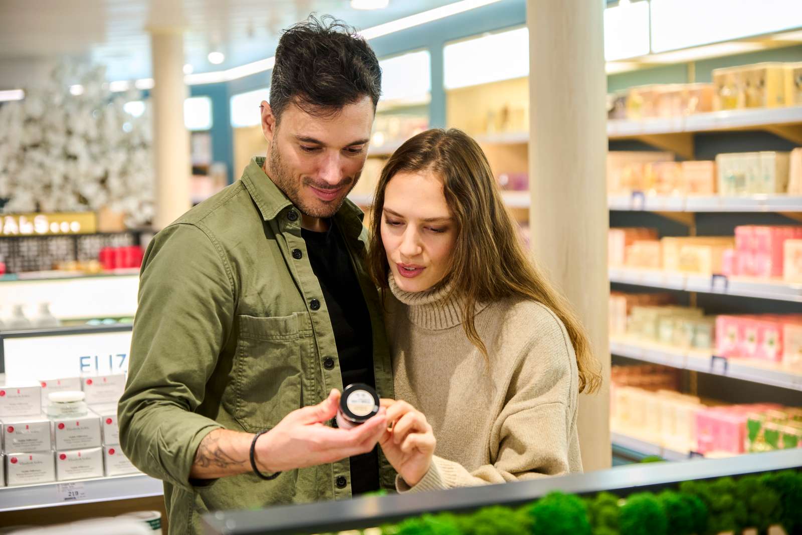 Par i butik undersøger en krukke hudplejeprodukt sammen med interesse.