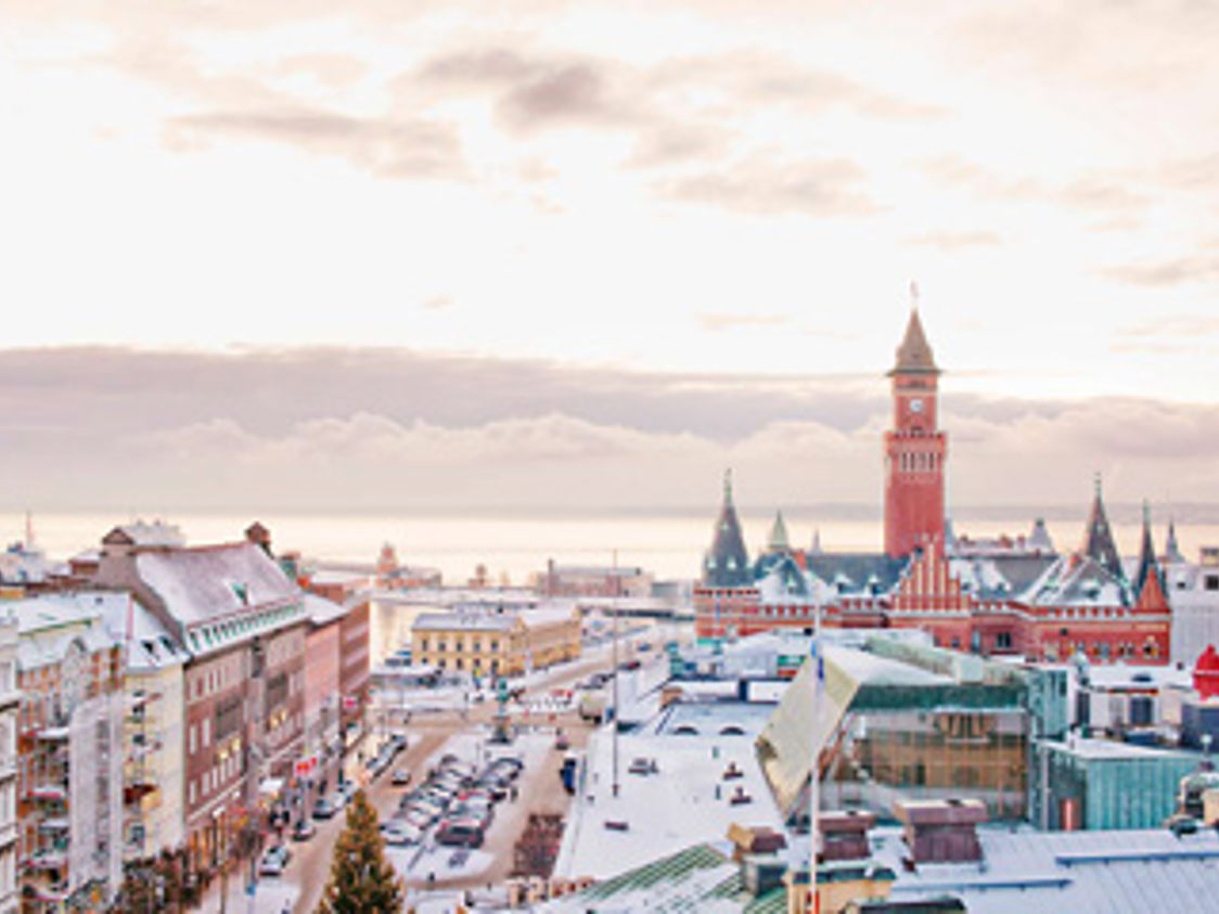 Helstenskys rådhus ses fra oven en vinterdag med sneklædte tage og en smuk horisont i baggrunden.