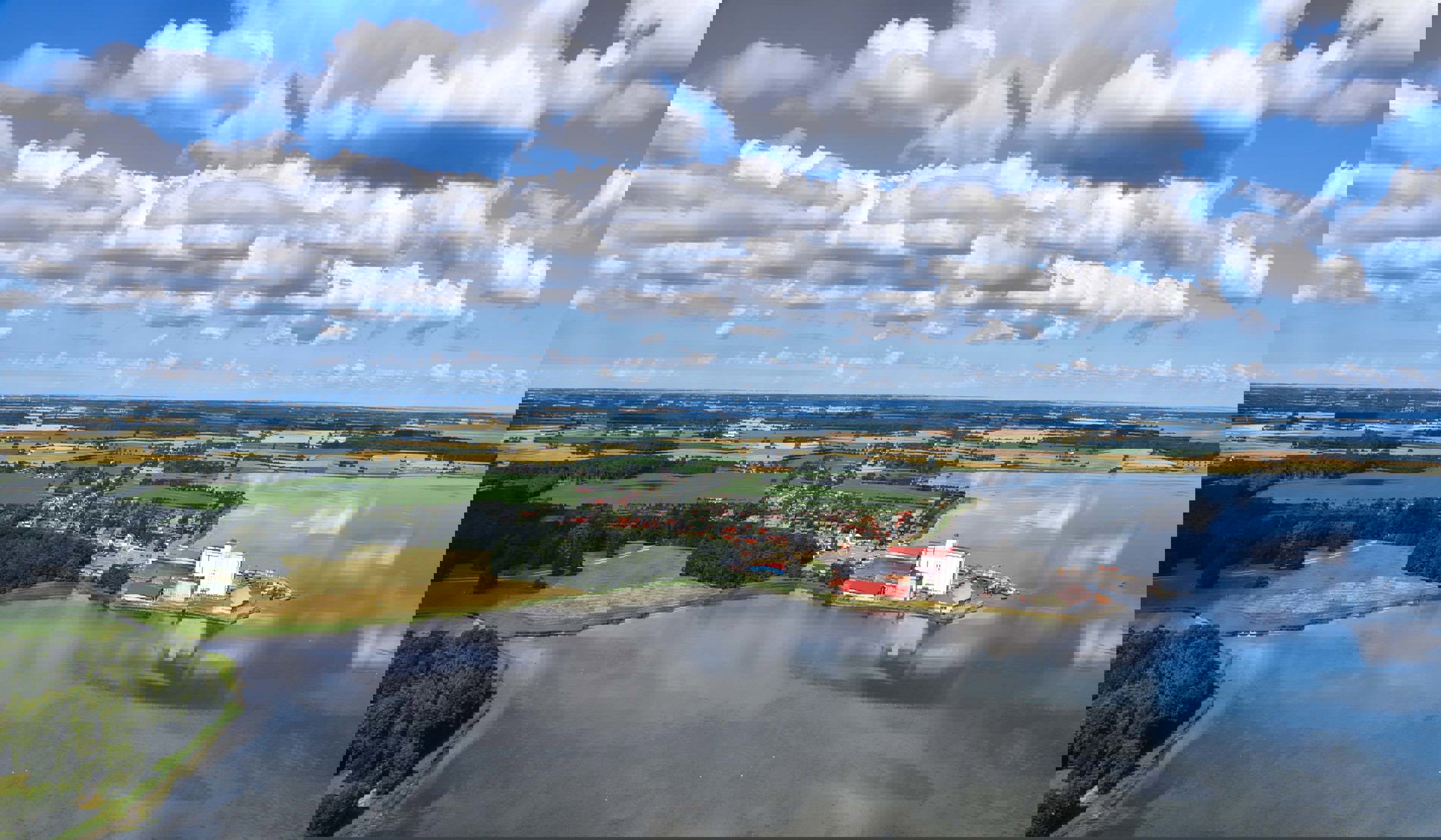 Fugleperspektiv af hav, skov og gule marker.