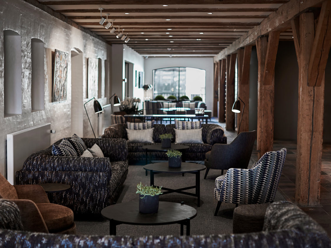Moderne hotel lounge med mørke møbler og træbjælker i loftet, set fra en indbydende vinkel.