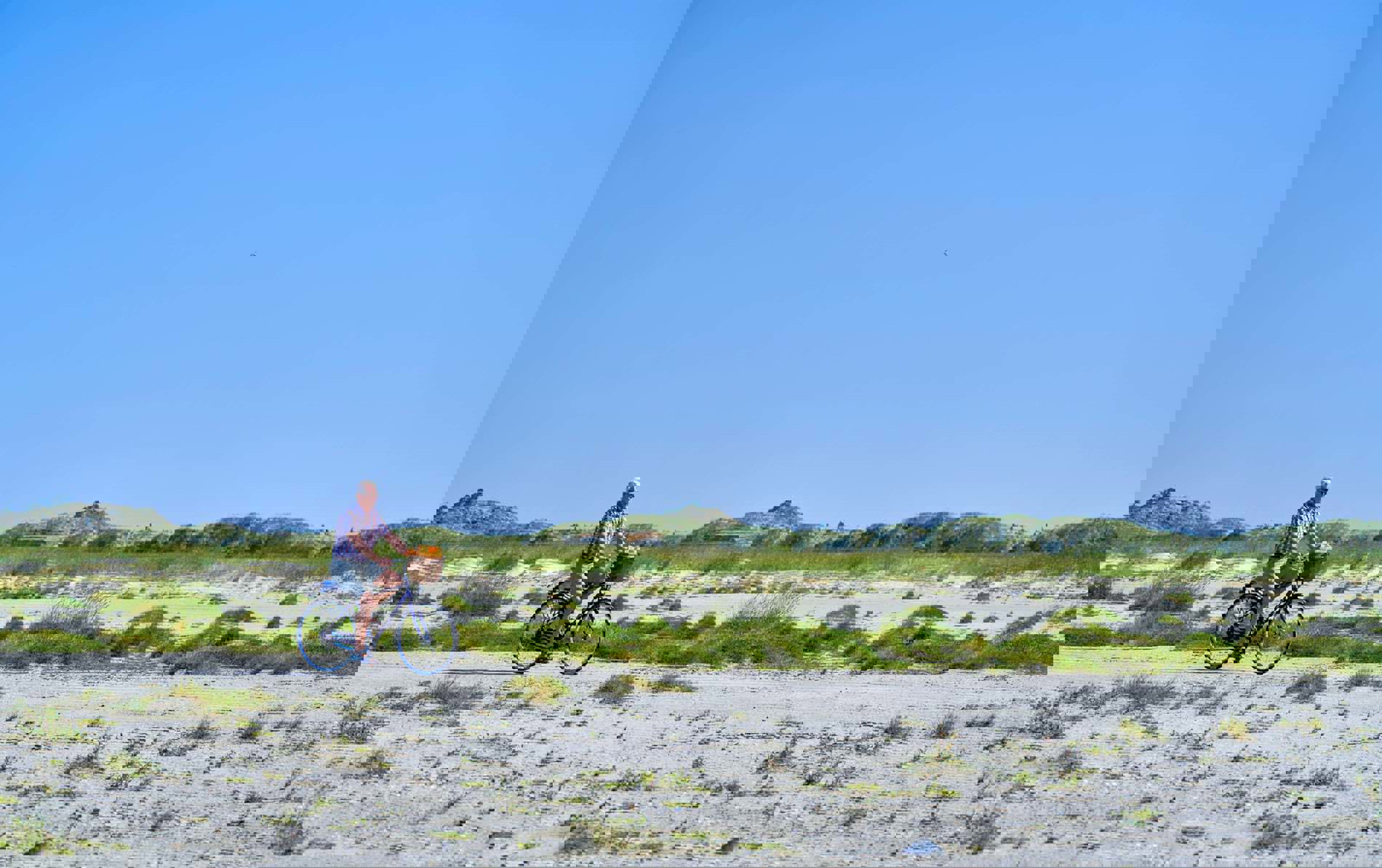 En cykel ses cykle fra venstre mod højre over billede på en af Fanøs strande.
