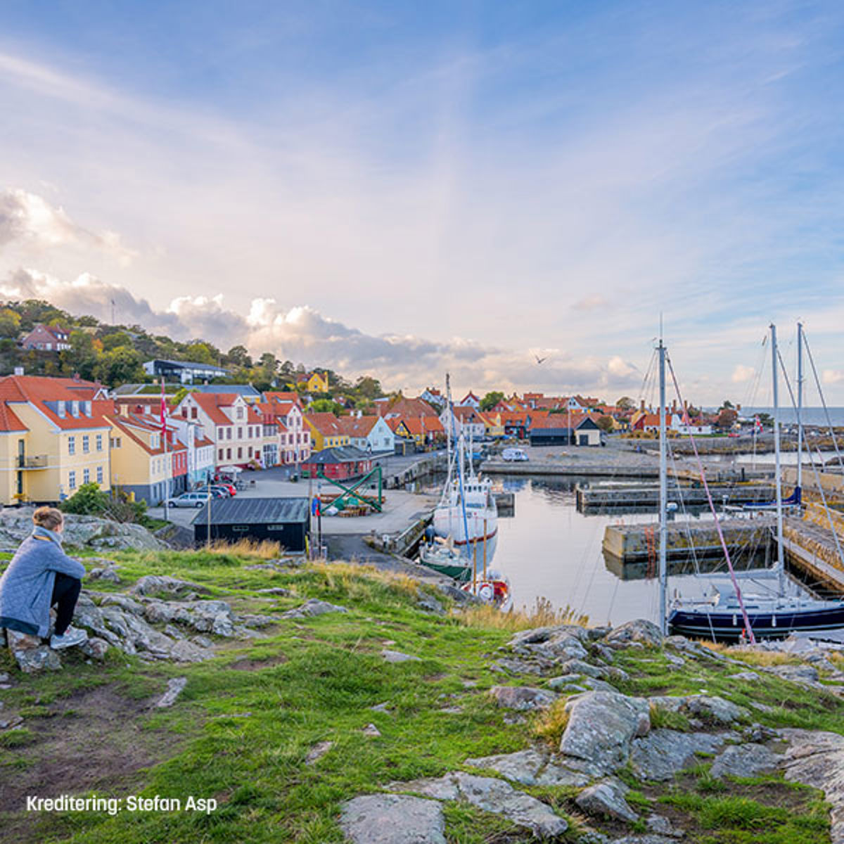 Udsigt over Allinge havn med sejlbåde og farverige huse i solrigt vejr på Bornholm.