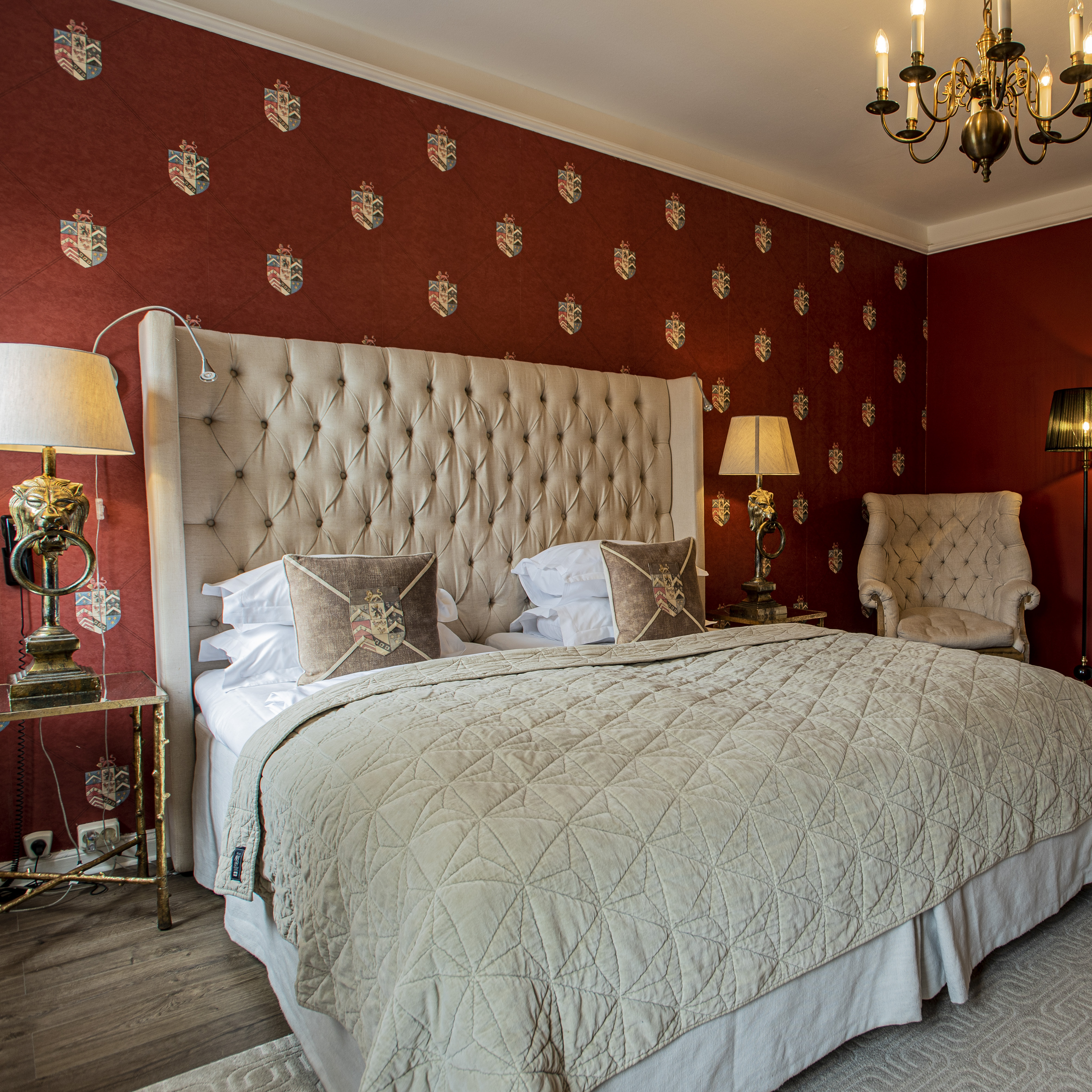 Elegant dobbeltværelse med polstret sengegavl og luksuriøst sengetøj i en klassisk indrettet suite.