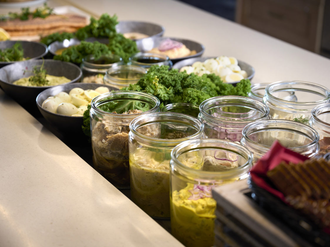 Sund frukostbuffé med färska grönsaker, ägg och sallader i glas och skålar på modernt köksbord i matsal.