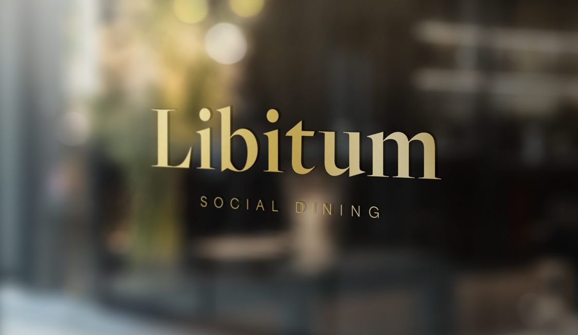Libitum social dining logo på cafeens vindue i en by.
