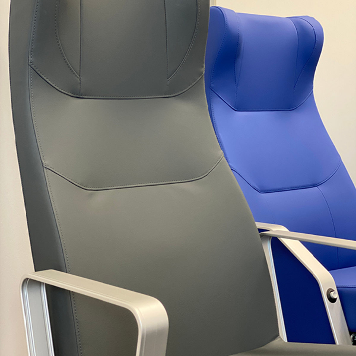 Grå og blå færgestole med høje ryglæn og armlæn i minimalistisk design.