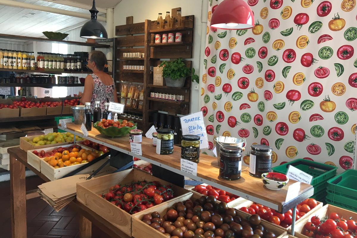 En butik viser en masse tomater og grøntsager i trækasser.