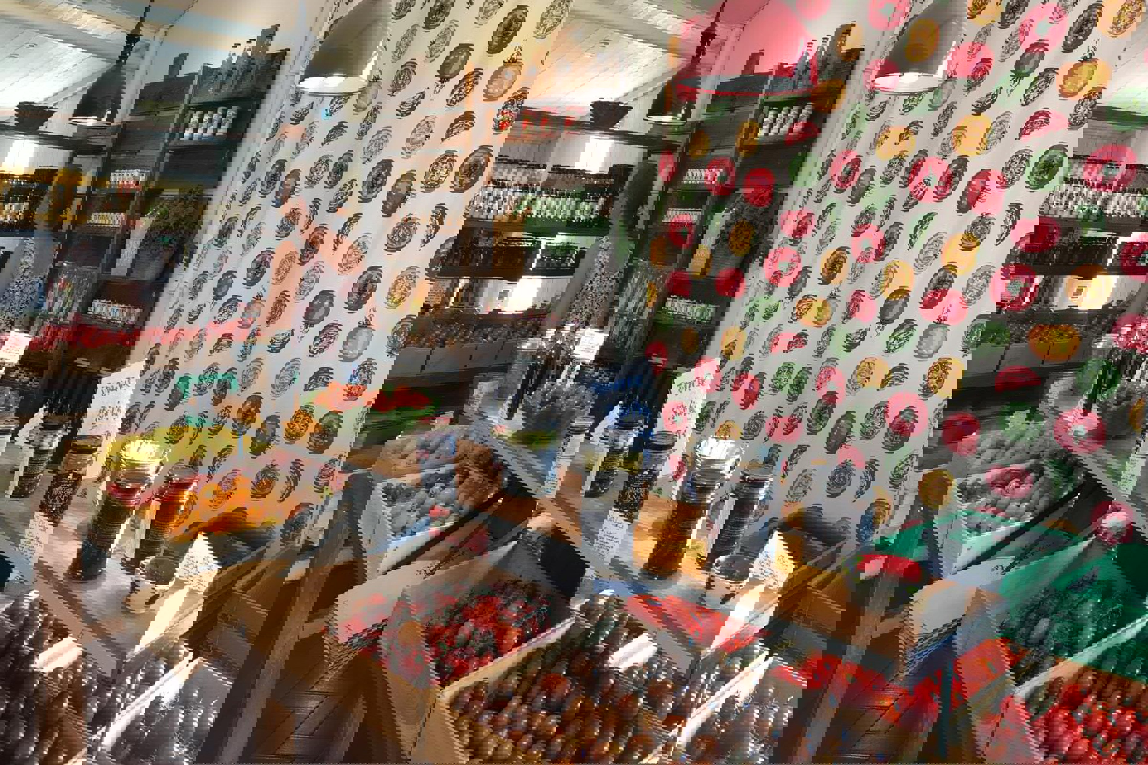 En butik viser en masse tomater og grøntsager i trækasser.