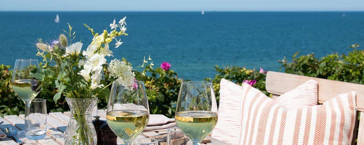 Ett bord dukat med blommor som blickar ut över havet.