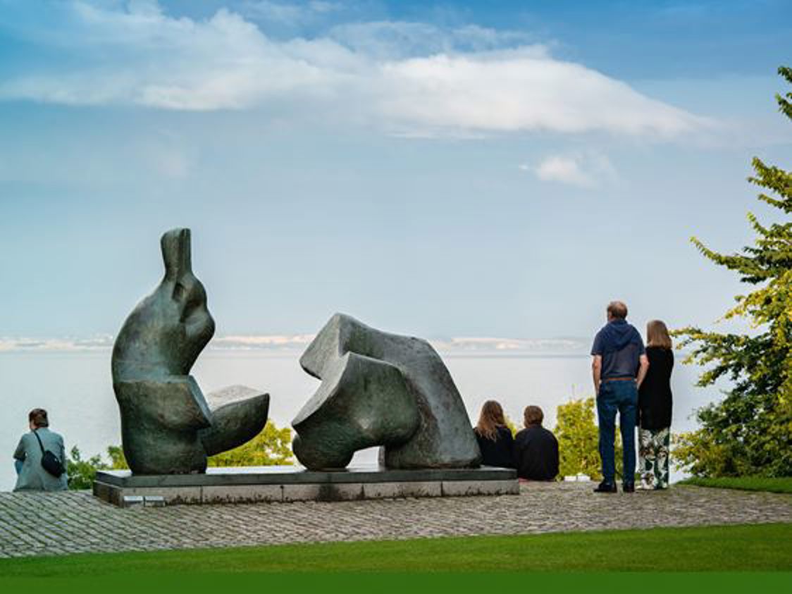Skulpturen Kim 0272 Edit i förgrunden vid havet med människor som beundrar konsten och utsikten.