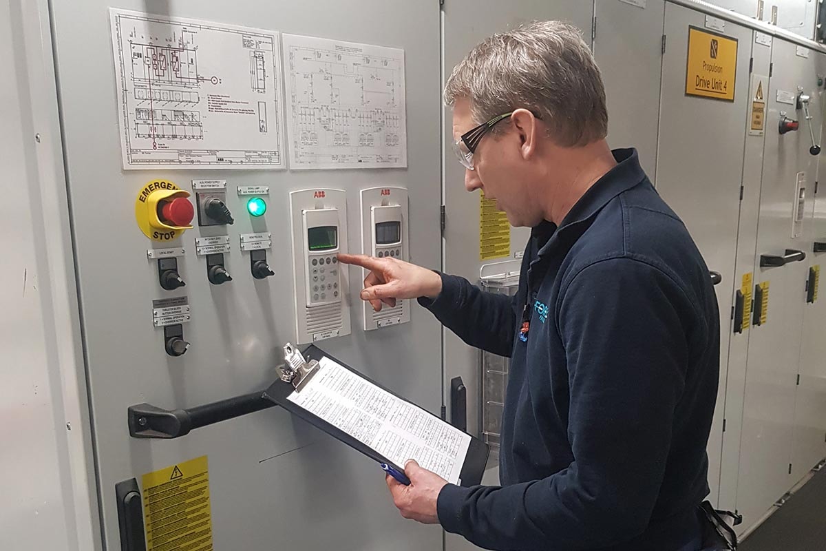 En person utför en säkerhetsinspektion i maskinrummet på en färja.