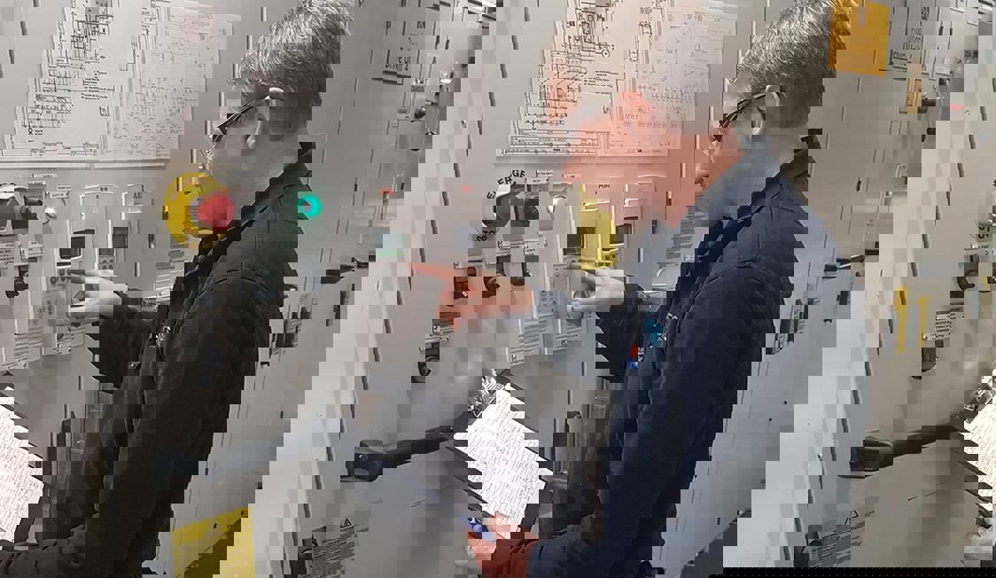 En person utför en säkerhetsinspektion i maskinrummet på en färja.