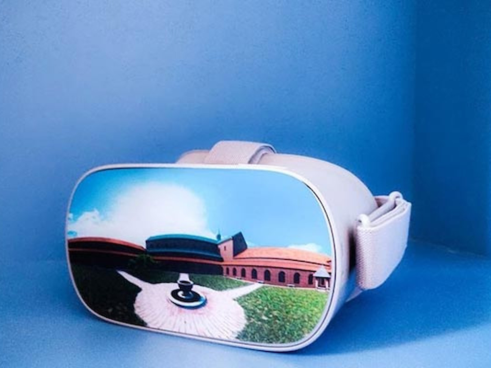 Vit Esrum VR-glasögon mot blå bakgrund med en bild av en byggnad på skärmen.