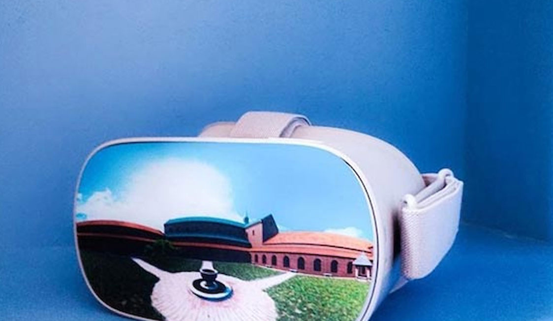 Vit Esrum VR-glasögon mot blå bakgrund med en bild av en byggnad på skärmen.