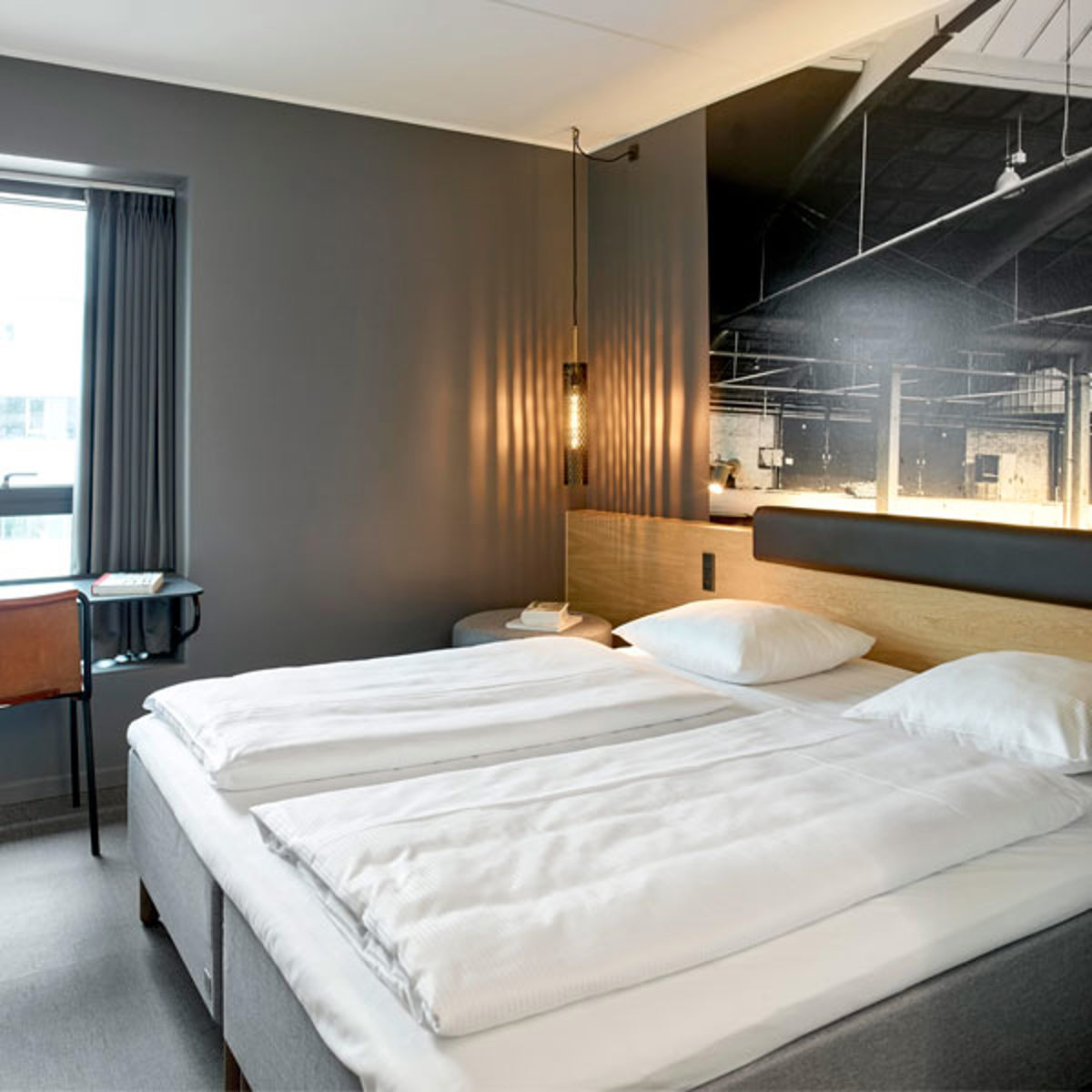 Moderne hotelværelse med dobbeltseng, elegant belysning og minimalistisk indretning i neutrale farver.