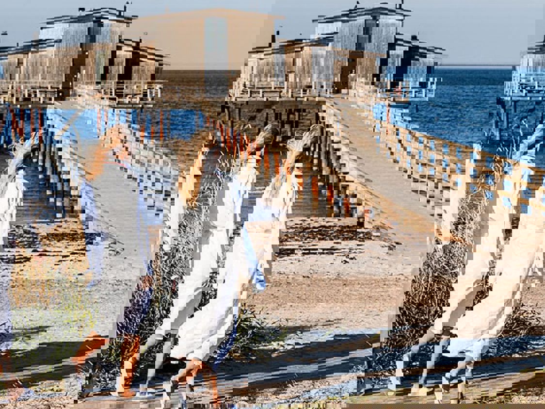 To blone kvinder i morgenkåber ses gående ud mod badebroen ved Hotel Skansen.