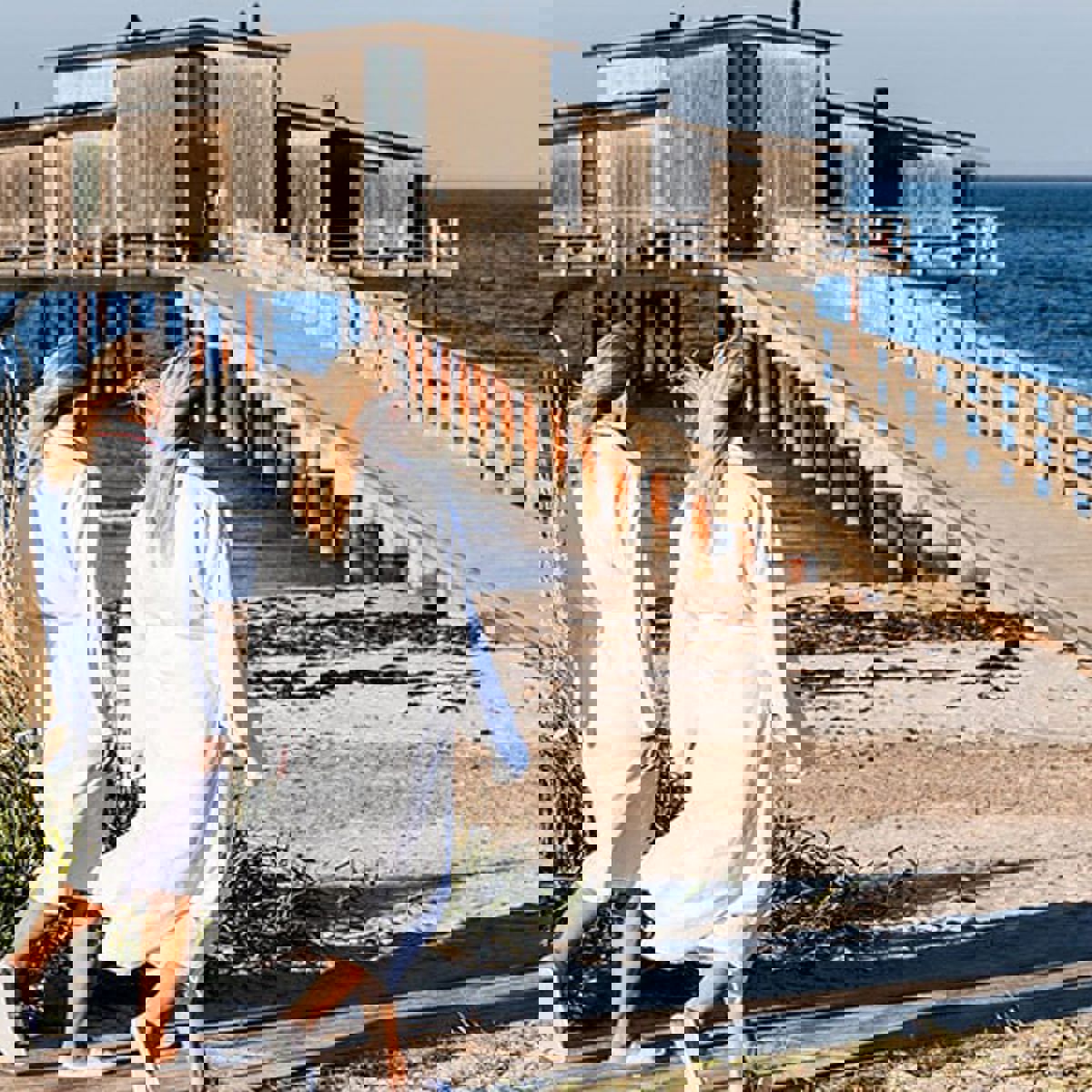 To blone kvinder i morgenkåber ses gående ud mod badebroen ved Hotel Skansen.