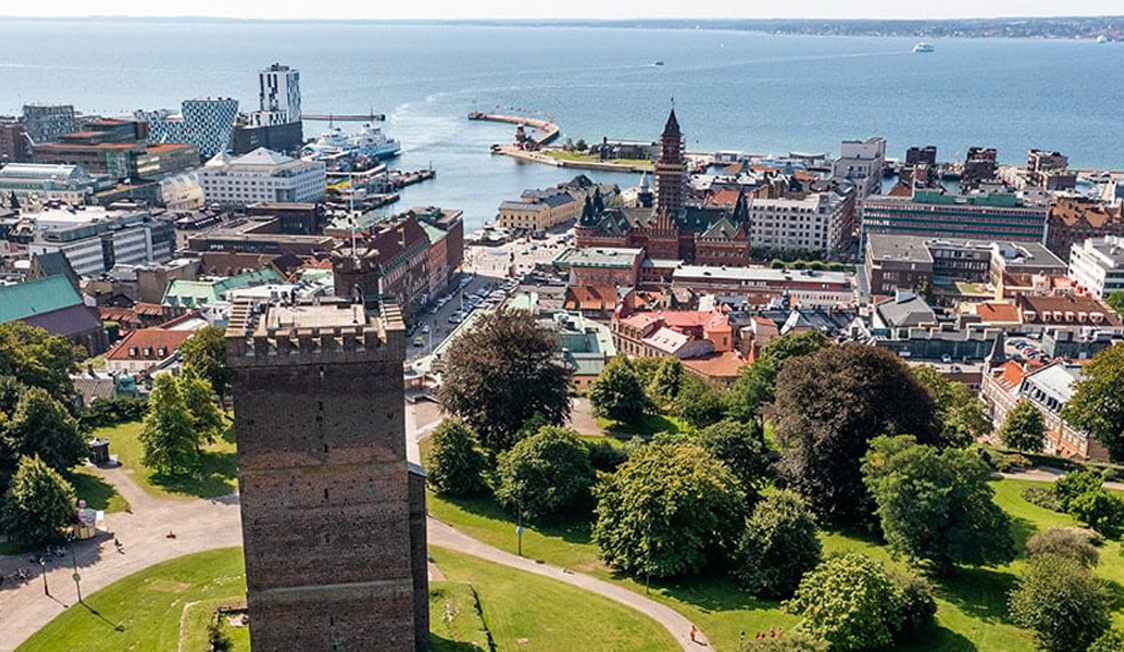 View from Kärnan tower over Helsingborg city center towards the sea, featuring historic buildings and park landscape.