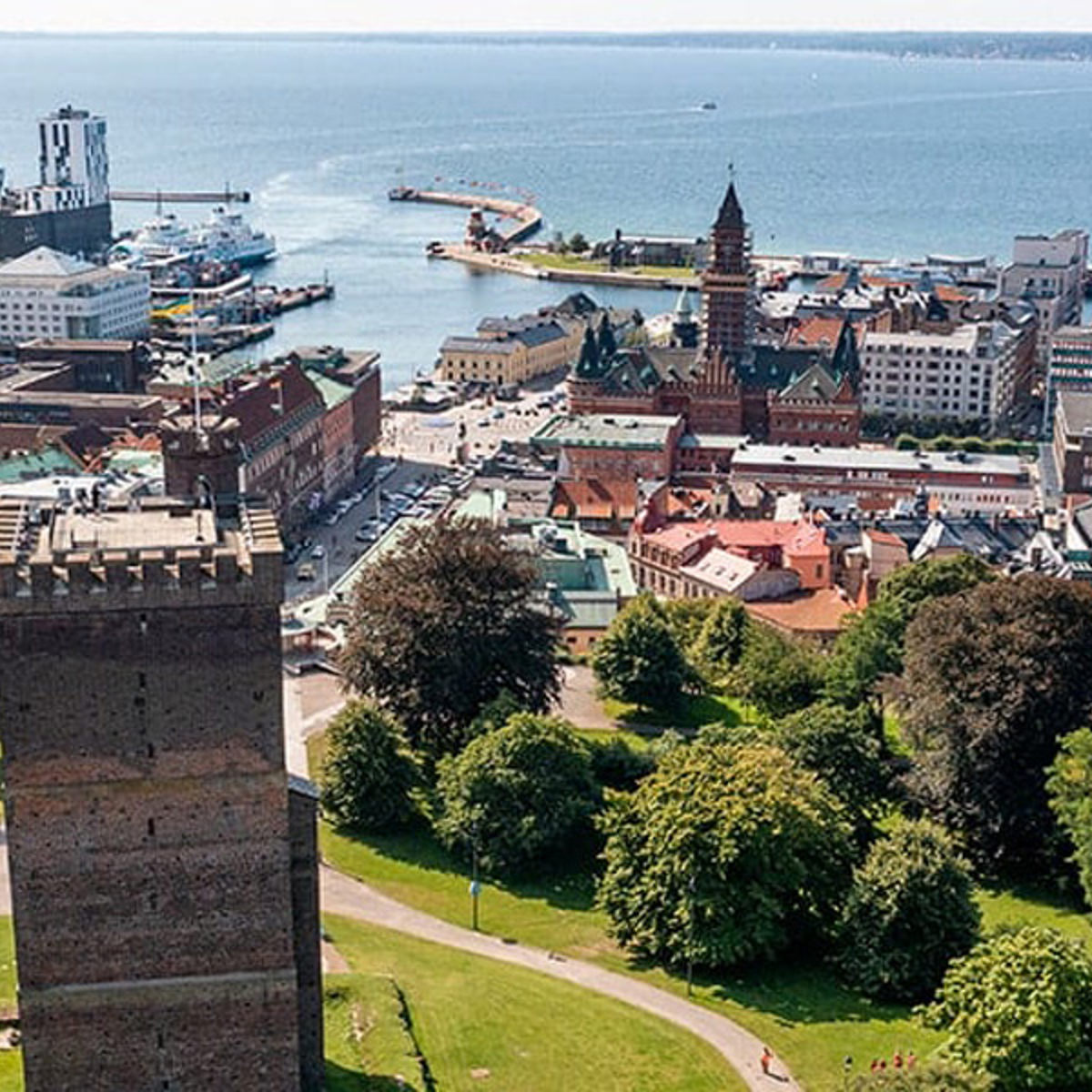 View from Kärnan tower over Helsingborg city center towards the sea, featuring historic buildings and park landscape.