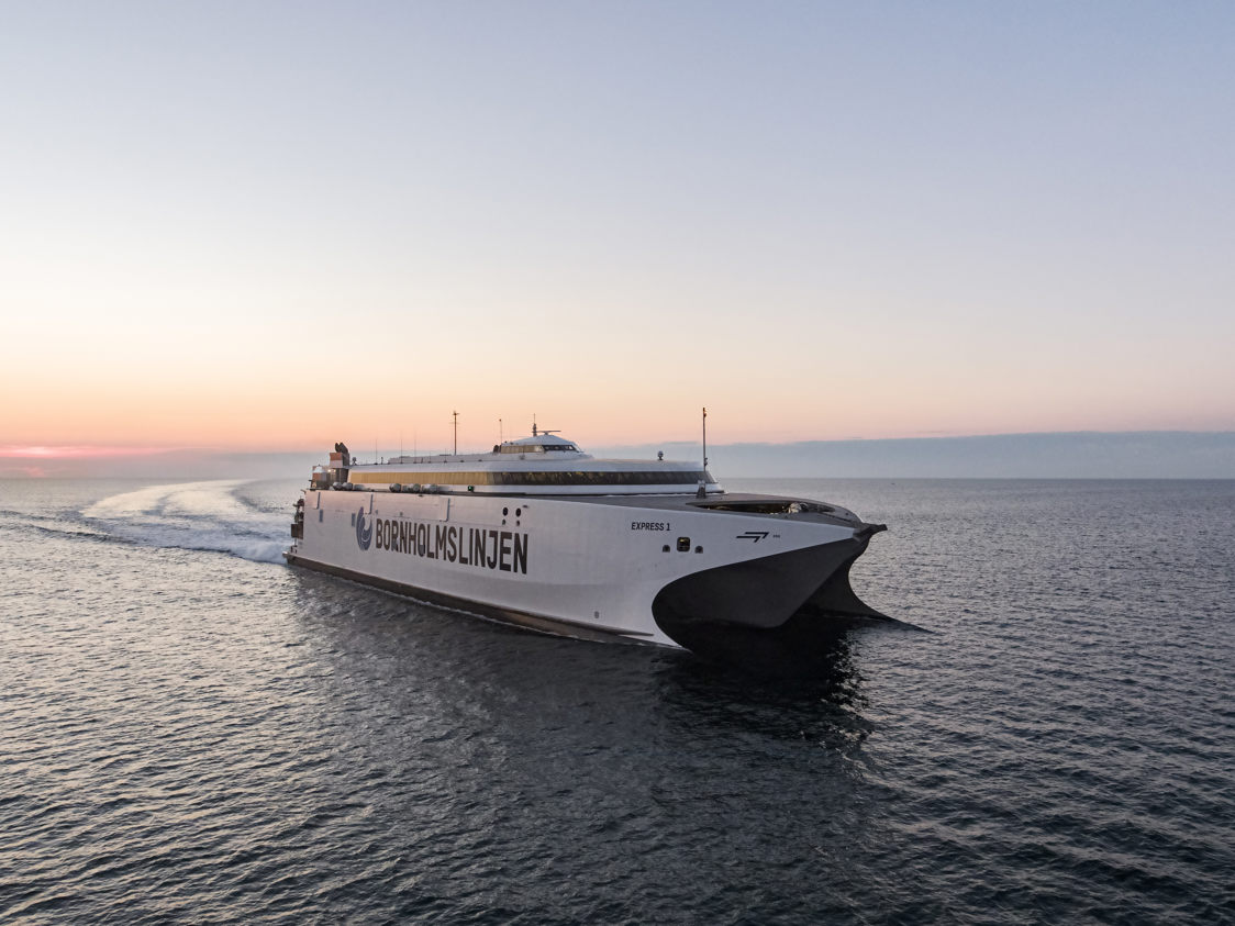 Bornholmslinjen færge Express 1 sejler på åbent hav ved solnedgang i fugleperspektiv.