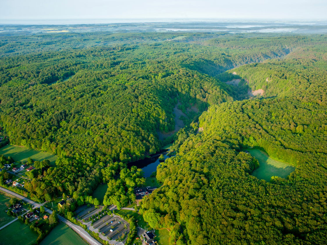 Flyfoto af frodig grøn skovlandskab i højderne med små søer og landsbyer i Århus-området i Danmark.