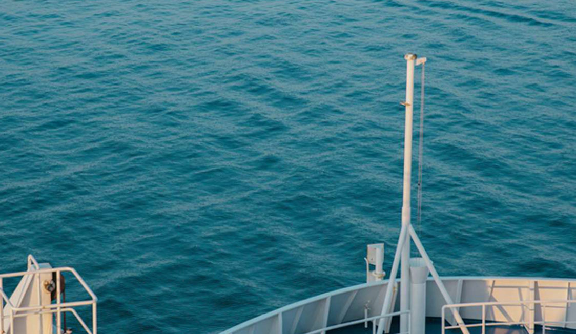 Skibsbue på åbent hav set fra oven med blåt hav i baggrunden.